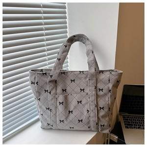 Detail of dark grey corduroy tote bag with black bow print and quilted stitching pattern