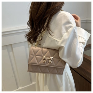 Close-up of quilted pattern and gold bow buckle on apricot shoulder bag