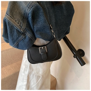 Close-up of black lychee grain leather underarm bag with decorative silver buckle