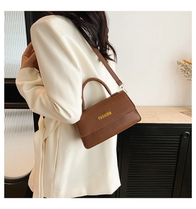 Brown litchi leather bag with FASHION text shown on a model for size scale