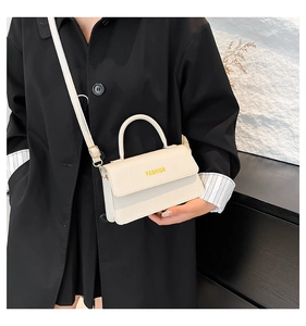 Detail view of a cream mini crossbody bag with litchi texture and gold hardware