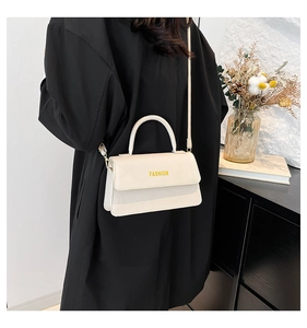 Detail view of cream white textured leather handbag with FASHION logo and handle