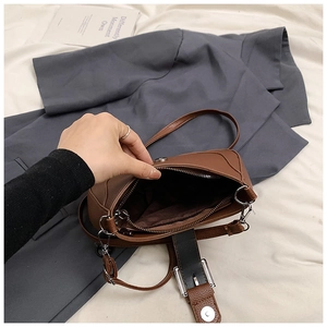 Detail view of brown pebbled leather crescent bag showing internal zipper and magnetic closure