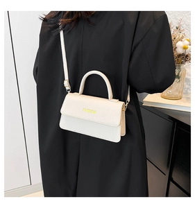 Detail of a beige lychee pattern handbag with fashion text and golden metal accessories
