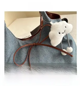Détails de coutures en denim bleu et cuir marron avec charm nuage en peluche décoratif