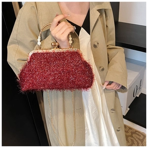 Détail du sac de soirée bordeaux avec texture brillante et poignée ronde dorée