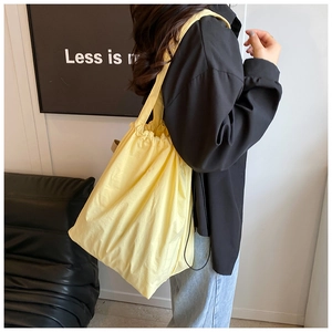 Detail view of the yellow nylon bucket bag showing soft texture and adjustable strap