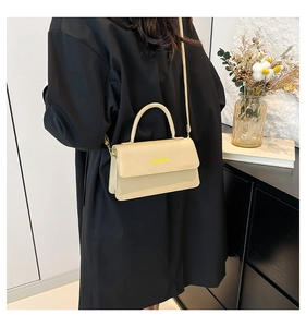 Detail shot of beige faux leather handbag with yellow FASHION text and sleek strap