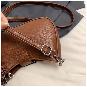Detail of brown litchi pattern leather texture with silver metal buckles on crossbody bag