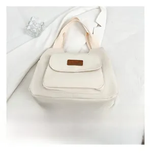 Dettaglio della borsa tote in tela bianca con tasca frontale e stemma Fashion applicato