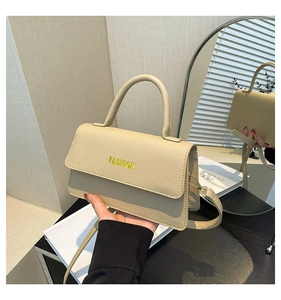 Close-up of beige lychee grain handbag with yellow FASHION text and metal strap clips