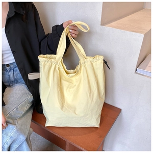 Detail of light yellow nylon bucket bag showing soft texture and drawstring feature