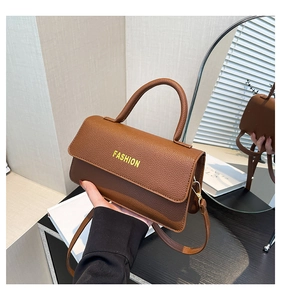 Close-up of brown litchi pattern leather handbag with gold hardware and FASHION logo