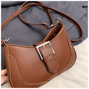 Detail of brown crescent bag showing pebble leather texture and silver buckle