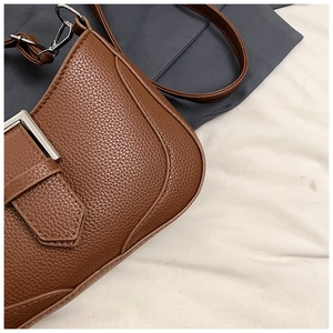 Detailed macro view of brown lychee grain leather with polished silver metal buckle hardware