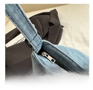 Detailed close-up of smooth metal zipper and denim texture on light blue tote bag