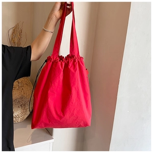 Detail of red drawstring nylon tote bag showing textured fabric and cinched closure