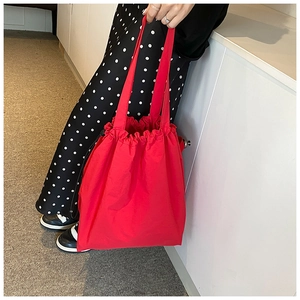 Detail of red nylon drawstring bucket bag showing texture and pleated closure