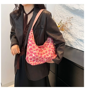 Dettaglio della borsa hobo rosa con stampa leopardata a cuore e blazer scuro