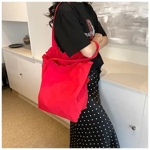 Detail of a bright red nylon bucket bag showing the large capacity and drawstring ruffles