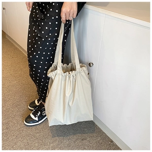 Close-up of beige nylon bucket bag with drawstring closure and large capacity design