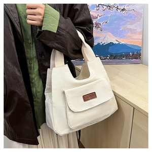 Dettaglio della borsa tote in tela bianca con etichetta fashion e tasca frontale