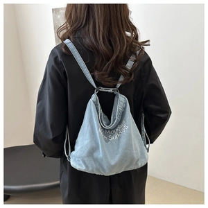 Detail of light blue denim tote bag featuring white text More Mondays More Sundays print