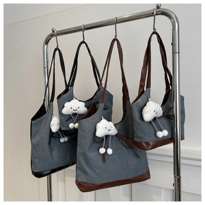 Détail d'un sac cabas en denim et cuir avec un pendentif nuage en peluche mignon