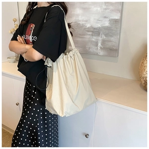 Detail of cream nylon bucket bag with drawstring closure and wide shoulder strap