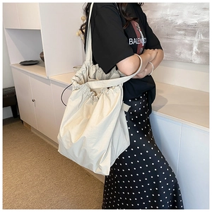 Detail view of large cream nylon tote bag featuring a stylish drawstring closure and texture
