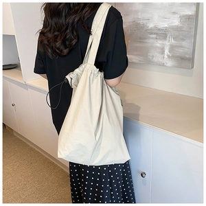 Detail of off-white nylon drawstring bucket bag with thick shoulder strap for daily commuting