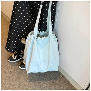 Detail of light blue nylon bucket bag with drawstring closure and wide shoulder strap