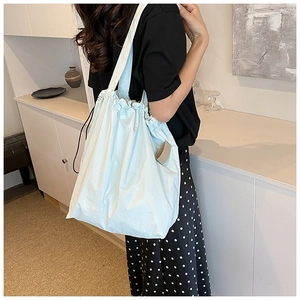 Close-up of mint blue nylon bucket bag with drawstring closure on model's shoulder