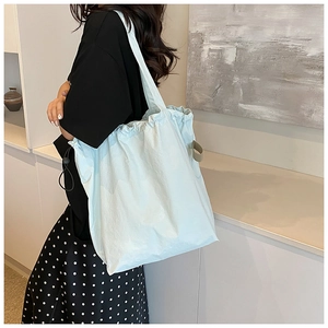 Close-up of a mint green nylon bucket bag with drawstring detail and a wide strap