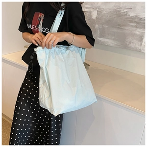 Detail of mint blue nylon bucket bag with black drawstring closure and wide shoulder strap