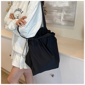 Detailed view of black nylon drawstring bucket bag on model for casual commuting style