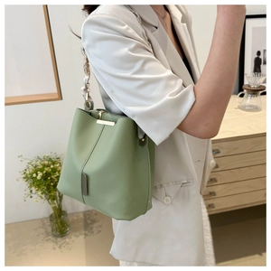 Detail of light green bucket bag featuring a decorative silk scarf wrapped chain strap