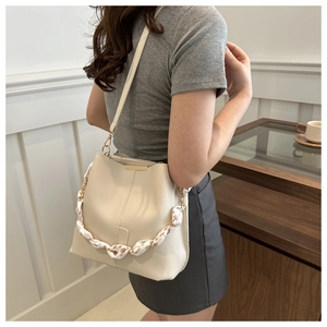 Detail of cream leather bucket bag featuring chain strap wrapped in floral silk scarf
