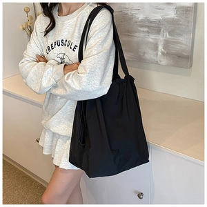Lifestyle shot of black nylon bucket bag with drawstring closure worn by a model