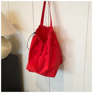 Detail of red nylon drawstring bucket bag with reinforced stitching on a wall