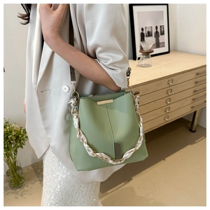 Detail of light green bucket bag showing gold metal bar and silk scarf chain strap
