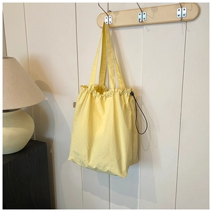 Detail of light yellow nylon bucket bag with drawstring closure and black adjuster