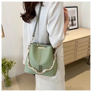 Detail of light green bucket bag featuring a silk scarf wrapped chain and slim leather strap