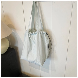Detail view of light blue nylon bucket bag with black drawstring and adjustable buckle