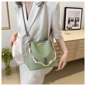 Detail of light green bucket bag with golden chain and floral silk scarf handle decoration