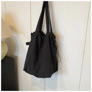 Close-up of the black nylon bucket bag featuring a drawstring closure and wrinkled texture