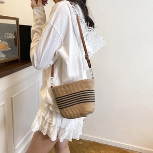 Fashionable woven bucket bag with black stripes and leather strap for beach vacations