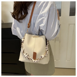 Detail of cream bucket bag with leopard scarf chain and adjustable leather strap