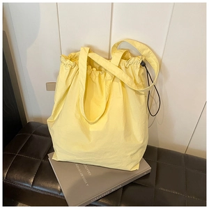 Detail of light yellow nylon bucket bag with drawstring closure and textured fabric