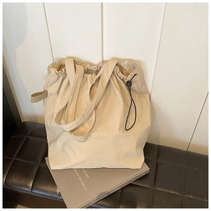 Detail of beige nylon bucket bag with black drawstring closure and soft texture